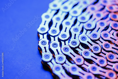 The texture of a shiny bicycle chain with a bluish-purple backlight