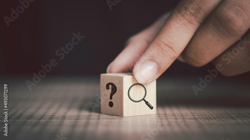 Hand flip magnifying glass and question mark sign icon in wooden cube. Problems and root cause analysis concept. copy space for background or text. photo