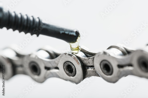 Fotografie Lubricating a bicycle chain with a drop of oil close-up on an isolated gray back