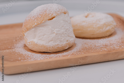 Soft buns filled with creamy are placed in a wooden dish sprinkled with icing sugar.Homemade confectionery,bakery business,baking school or cafe concept,high-energy snacks containing starch and sugar.