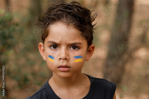 ritratto di un un bambino in contesto naturale  con la bandiera dell'Ucraina disegnata sul viso photo
