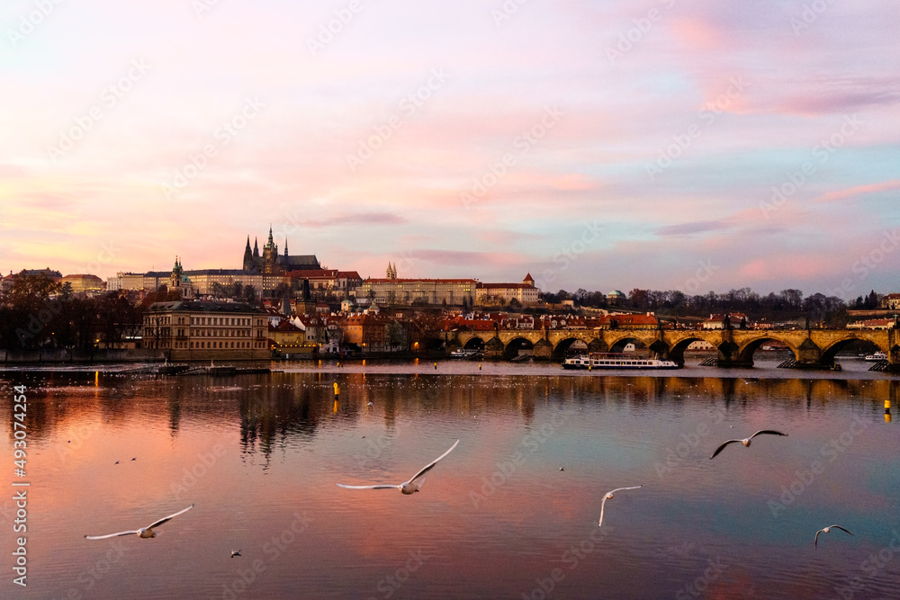 Prag, Tschechien, mit fliegenden Möwen in der Abenddämmerung; Stadtansicht Prag mit der Moldau und der Karlsbrücke und der Prager Burg im Hintergrund