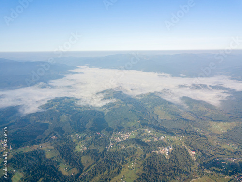 High flight in the mountains of the Ukrainian Carpathians. Fog in the valley. Aerial drone view.
