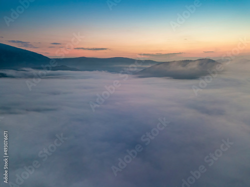 The rays of dawn over the fog in the Ukrainian Carpathians. Aerial drone view.