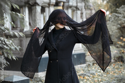 Portrait of a grieving woman in black with a veil on his face on the background of the Crypt.