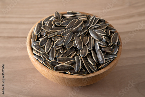 Black sunflower seeds in a bowl on wooden background	