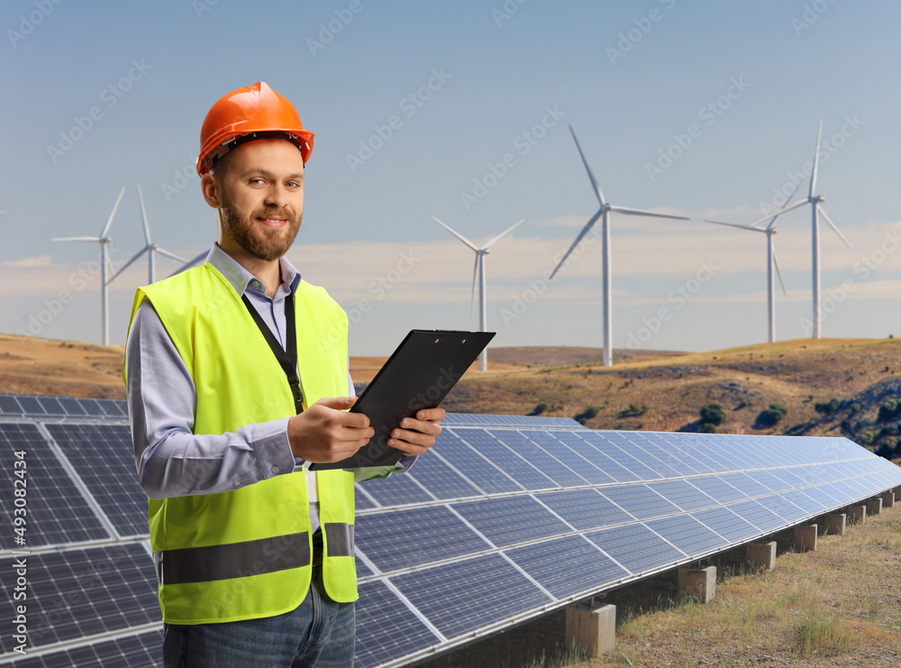 Engineer holding a clipboard on a sustainable solar and wind turbine farm Engineer holding a clipboard on a sustainable solar and wind turbine farm