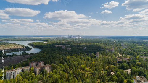 Aerial view abandoned buildings and streets overgrown with trees in city Pripyat near Chernobyl nuclear power plant. Drone shot Exclusion Zone in summer. Reactor under the sarcophagus. Radiation