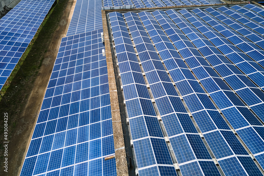 Aerial view of blue photovoltaic solar panels mounted on industrial building roof for producing green ecological electricity. Production of sustainable energy concept Aerial view of blue photovoltaic solar panels mounted on industrial building roof for producing green ecological electricity. Production of sustainable energy concept