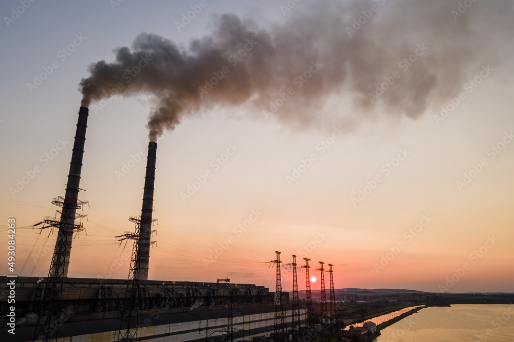 Aerial view of coal power plant high pipes with black smoke moving upwards polluting atmosphere at sunset. Production of electrical energy with fossil fuel concept Aerial view of coal power plant high pipes with black smoke moving upwards polluting atmosphere at sunset. Production of electrical energy with fossil fuel concept