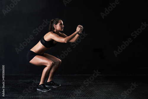 Shes got the squat. Studio shot of a woman working out against a dark background.