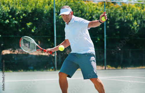 Staying healthy is a lifestyle. Cropped shot of a handsome mature man playing tennis alone on a court during the day. © Allistair/peopleimages.com