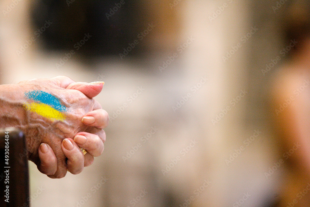due mani giunti in segno di preghiera e sopra i colori dell'Ucraina due mani giunti in segno di preghiera e sopra i colori dell'Ucraina