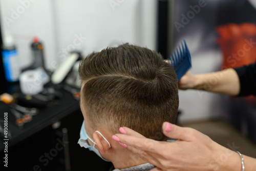 Hairdresser puts hair to teen boy after haircut, haircut for teen.