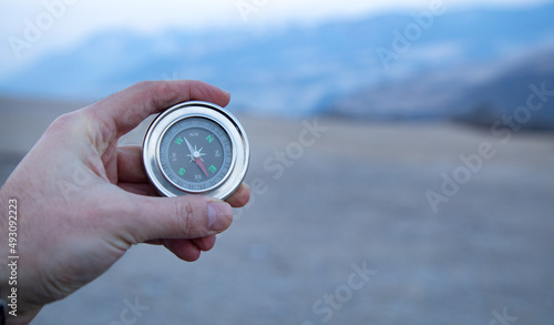 male traveler's hand holding a magnetic compass