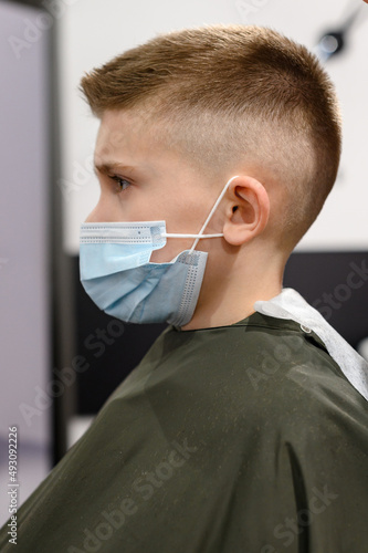 Schoolboy in a barbershop during a pandemic  stylish haircut for baby.