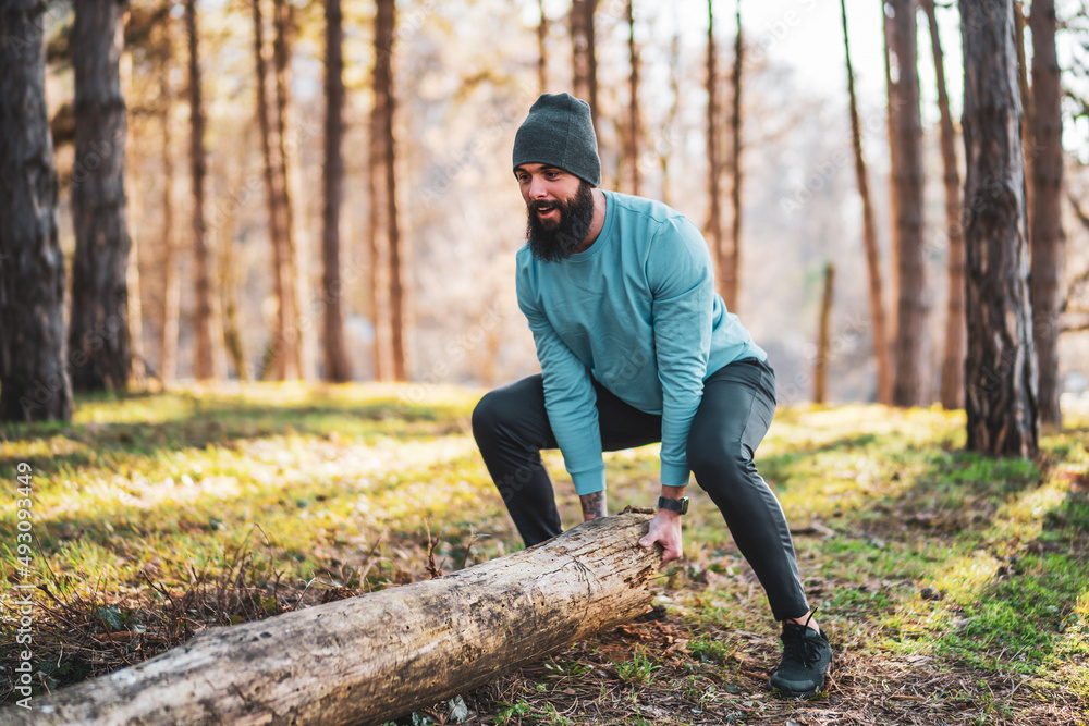 Strong sporty man is lifting tree stump . Strong sporty man is lifting tree stump .