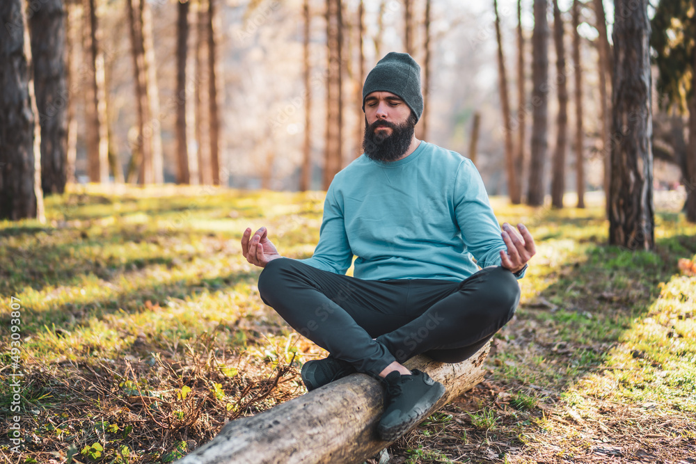 Sporty man enjoys meditating in the nature.