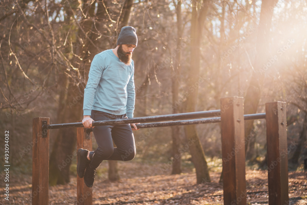 Man enjoys exercise push- ups on parallel bars in the park. Man enjoys exercise push- ups on parallel bars in the park.