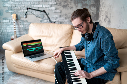 Image of male musician playing electronic piano and recording music at home studio. Concept of domestic hobby, entertainment and leisure. Young creative songwriter man 