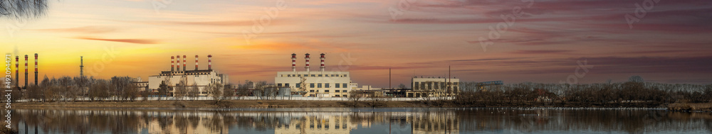 large industrial zone in the city, factories and nuclear power plants near the river at sunset.