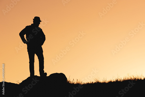 silhouette of waiting man in hat on orange background. hands to side