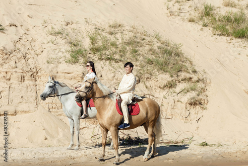 a guy and a girl on horseback on the river bank