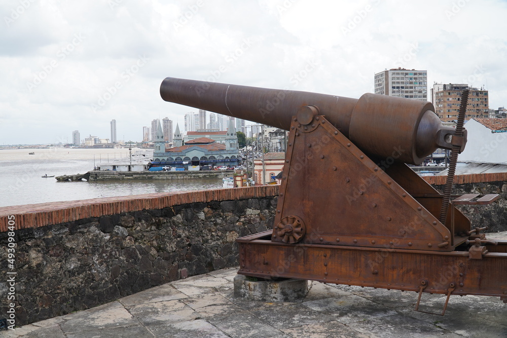 Cannon in the fort of the castle (Forte do Castelo), behind it the old Ver-O-Peso market and in the background modern skyscrapers, Belem, state of Para, Brazil. Cannon in the fort of the castle (Forte do Castelo), behind it the old Ver-O-Peso market and in the background modern skyscrapers, Belem, state of Para, Brazil.