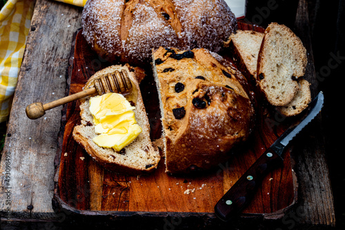 Round loaf of Irish soda bread sliced with slice of bread spread with butter and honey on a wooden dipper photo