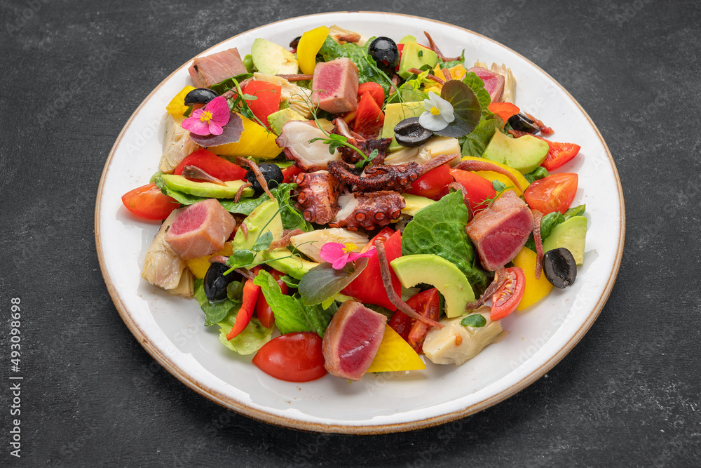 Salad with octopus, tuna and vegetables, on a dark background Salad with octopus, tuna and vegetables, on a dark background