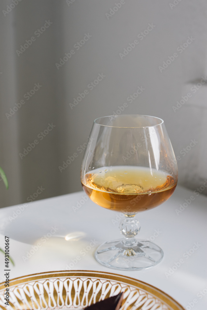 brandy snifter on white reflective table with white background by window brandy snifter on white reflective table with white background by window