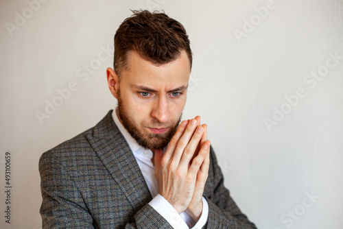 
a young man with a beard 25-35 in a suit is experiencing unpreparedness, fear, concern, deep in thought photo