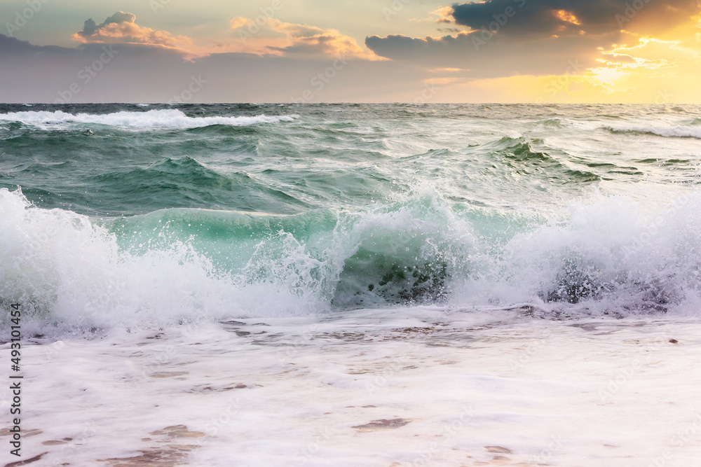 Obraz premium seascape with waves crashing the beach at sunrise. beautiful summer scenery at the sea in morning light