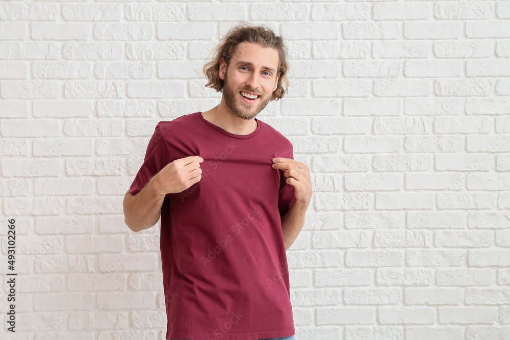 Handsome young man in t-shirt on white brick background Handsome young man in t-shirt on white brick background