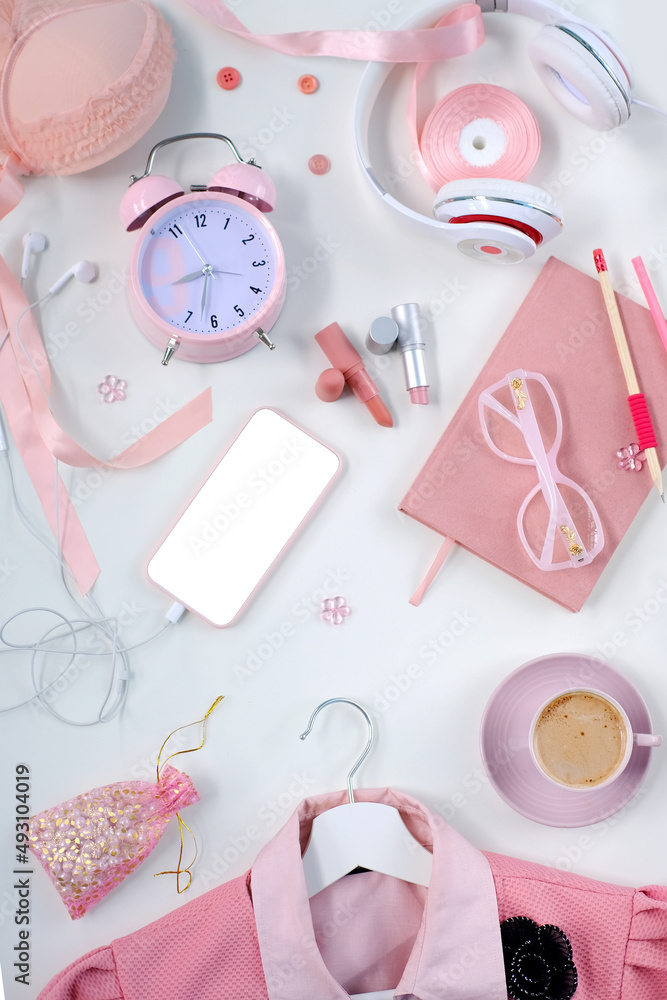 Fototapeta premium womens stylish accessories, smartphone with blank screen, glamorous set in pink shades, flat lay, copy background, womens clothing, alarm clock, lipstick, coffee cup, good morning concept, female life