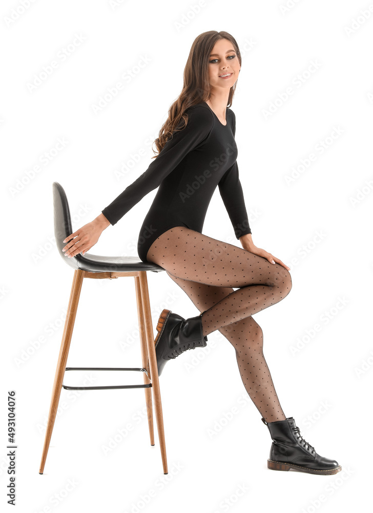 Beautiful young woman in black tights sitting on chair against white background Beautiful young woman in black tights sitting on chair against white background