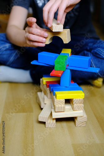 child, kid plays with colored wooden cubes, builds houses and rockets, the concept of the development of creativity, fine motor skills, patience and perseverance