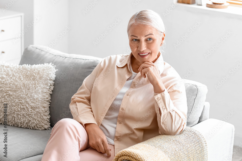 Mature woman sitting on soft sofa at home