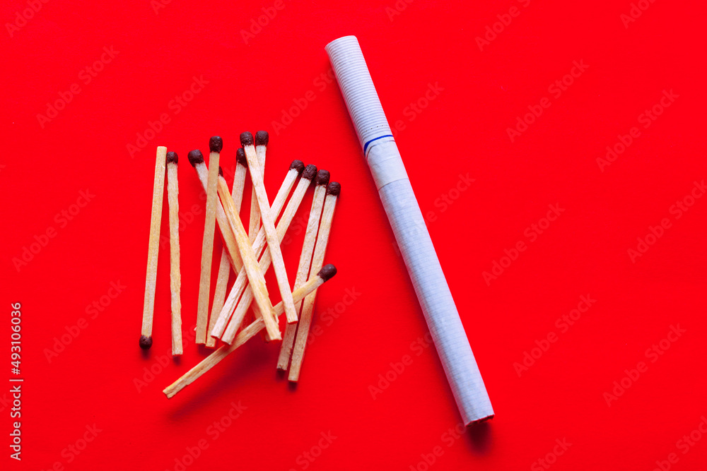 Obraz premium Tobacco cigarette and matches , red background 