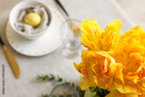 Bouquet of beautiful yellow tulips on table served for Easter celebration  closeup
