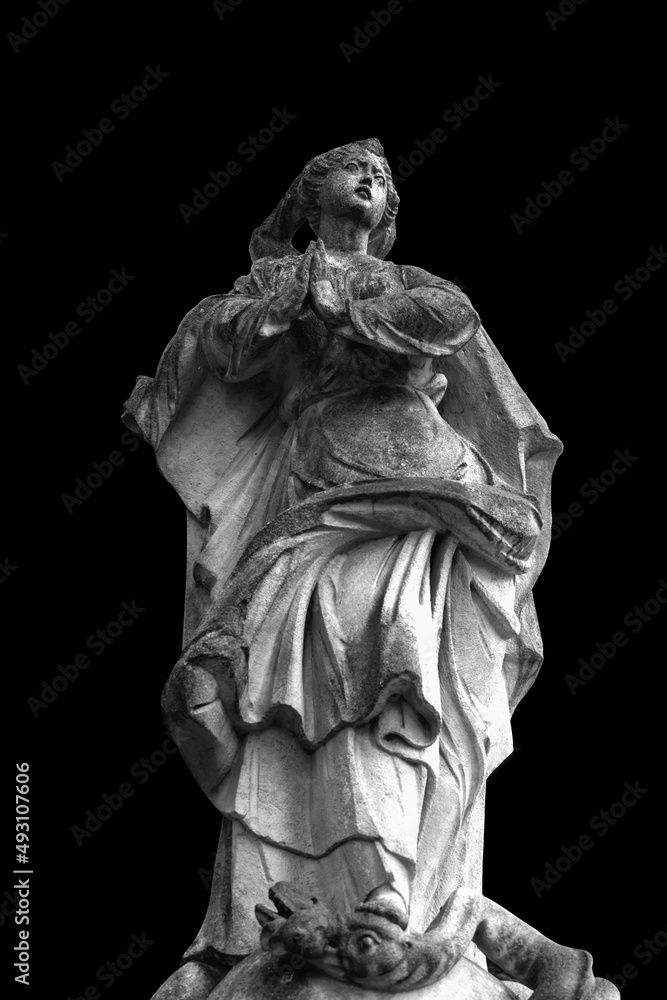 An ancient statue of Virgin Mary isolated on black background. Selective focus on eye. Black and white image.