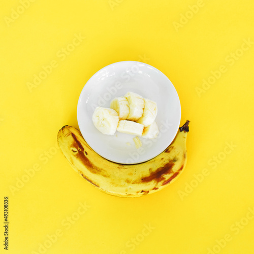 Bananas cut and placed on a white plate, on a yellow background. photo