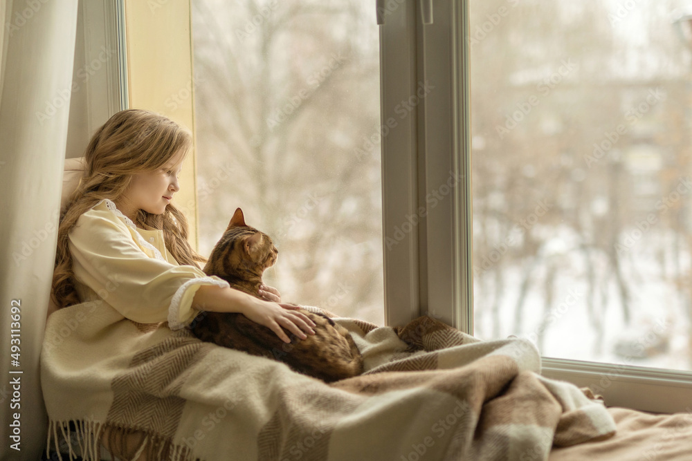 girl sits on the windowsill by the window with a cat girl sits on the windowsill by the window with a cat