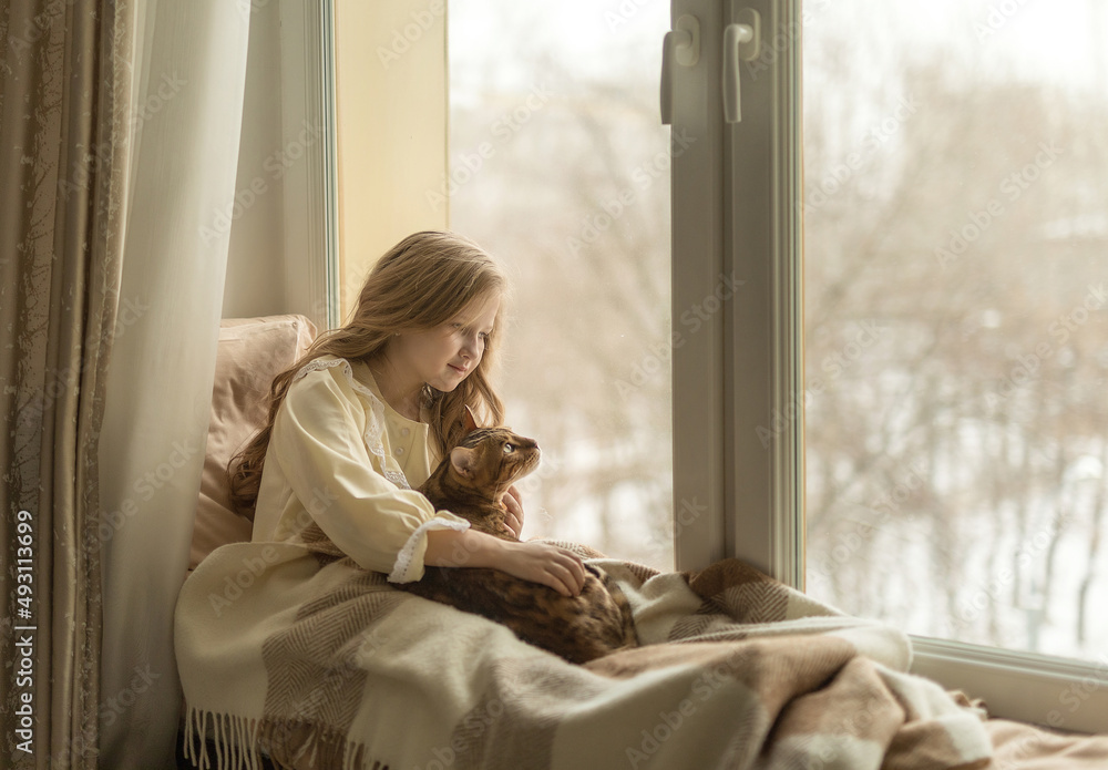 girl sits on the windowsill by the window with a cat girl sits on the windowsill by the window with a cat