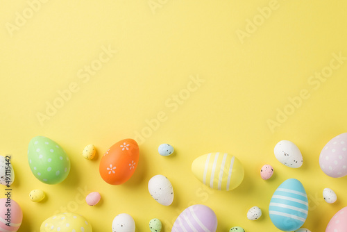 Top view of multicolored Easter eggs and quail ones situated on the isolated yellow background copyspace