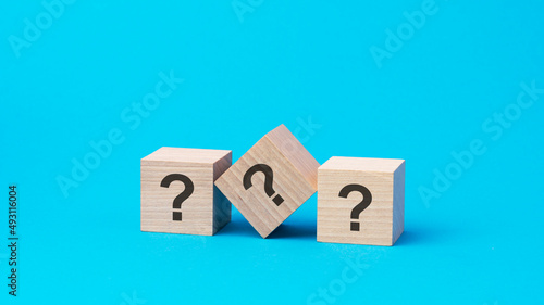 three question marks on wooden blocks, business concept, blue background