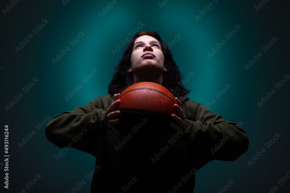 Teenage girl with basketball. Studio portrait with neon blue colored background.. Teenage girl with basketball. Studio portrait with neon blue colored background..