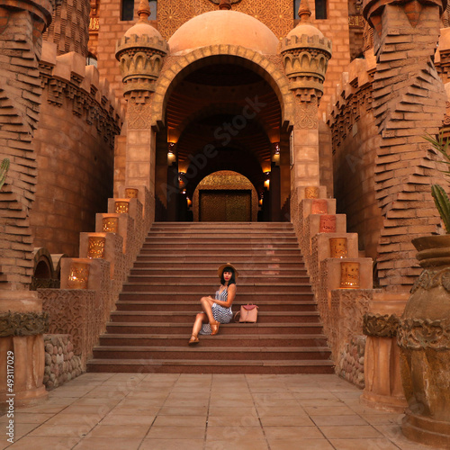 young girl on the background of the El Mustafa Mosque in the Old City of Egypt. woman sits on the steps of a mosque. Travel to Egypt concept. An ancient mosque in the tourist city of Sharm El Sheikh