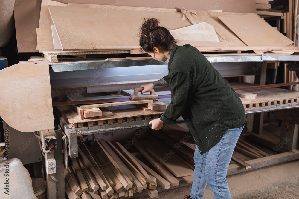 Carpenter polishing plank near boards in workshop. Carpenter polishing plank near boards in workshop.