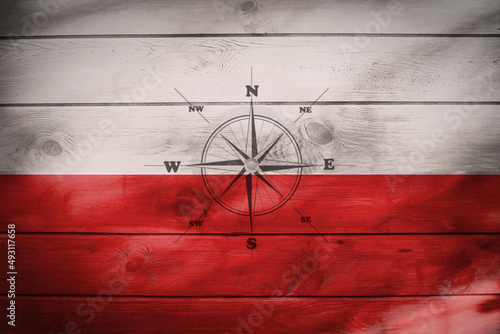 Flaga polski namalowana na drewnianych deskach z różą wiatrów.